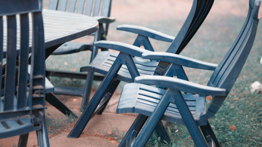 Blauwe kunststof tuinstoelen rond een houten tafel op een grasveld