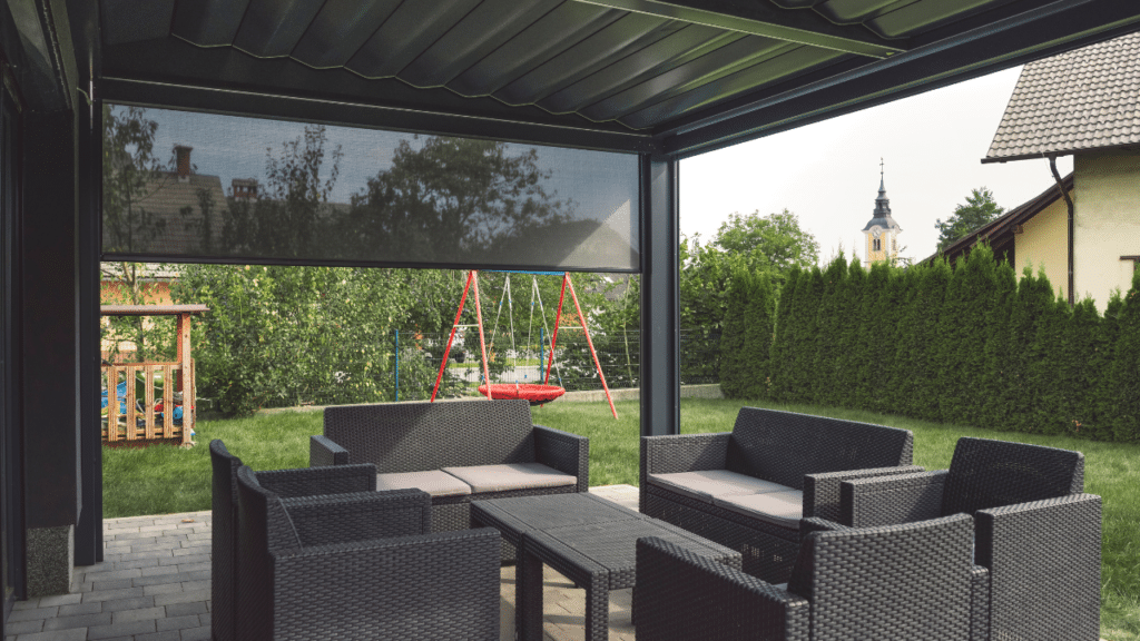 Boender Outdoor loungeset onder een overkapping met uitzicht op een tuin met schommel en groenblijvende haag.