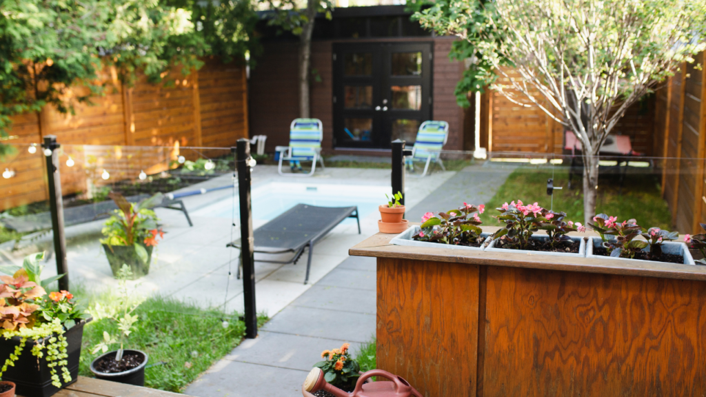 Gezellige achtertuin met houten omheining, ligstoelen en bloembakken met kleurrijke bloemen.