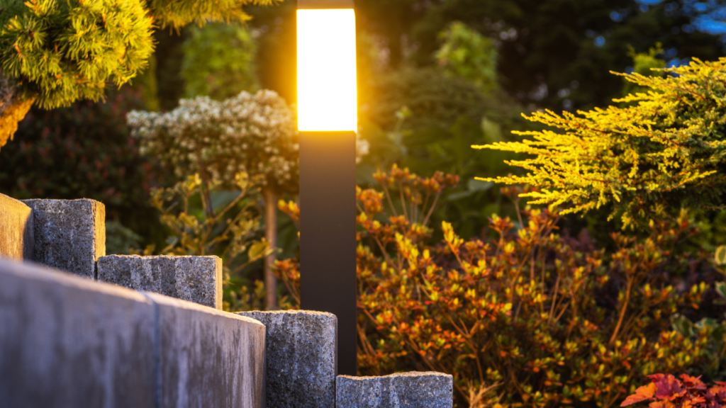 Verlichte tuinlamp langs stenen trap met kleurrijke beplanting bij zonsondergang